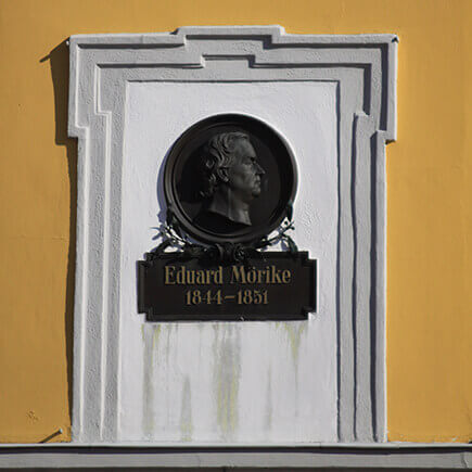 Wandtafel mit einem Bild von Eduard Mörike und der Inschrift 1844-1851 an der Wand eines Gebäudes in Bad Mergentheim.