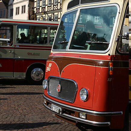 Zwei rote Oldtimerbusse beim Oldtimer Bustreffen auf dem Marktplatz in Bad Mergentheim.