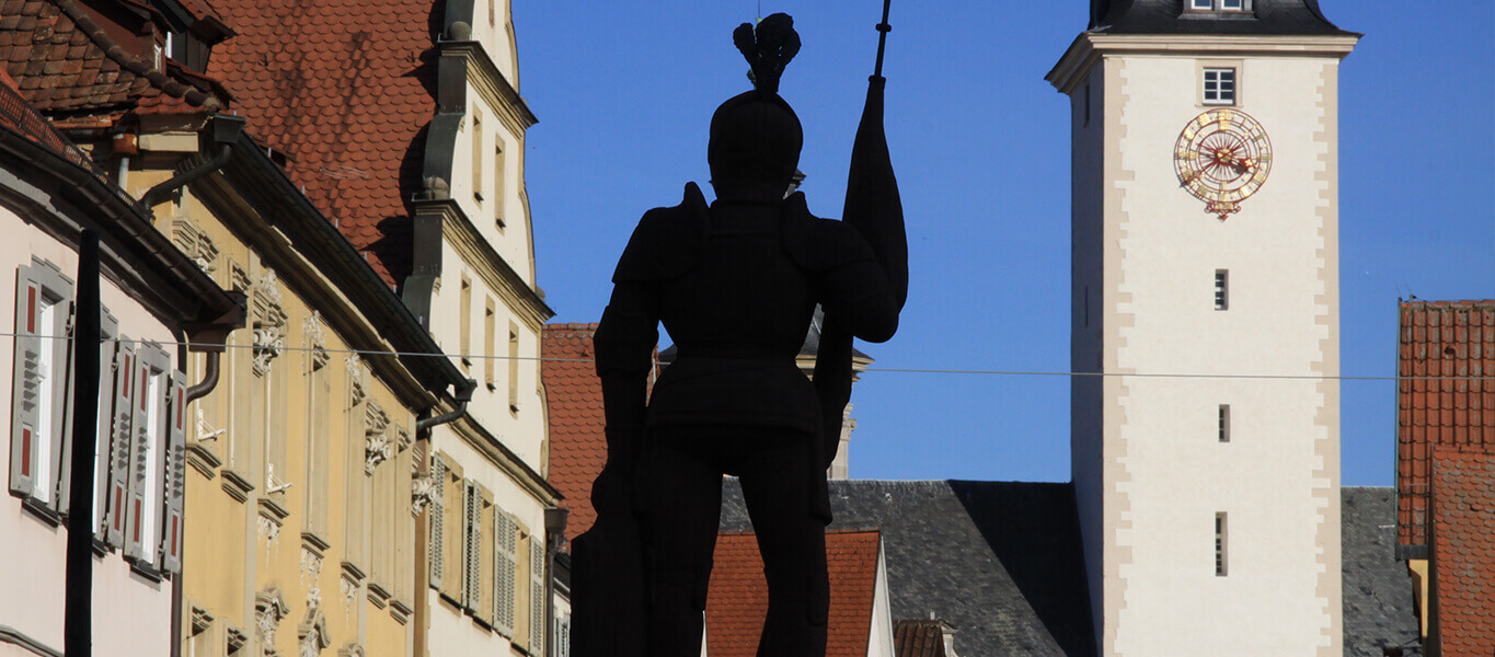 Die Statue des Milchlings im Vordergrund und im Hintergrund der Turm des Residenzschlosses.