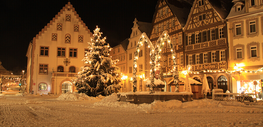 Verschneiter geschmückter Marktplatz mit altem Rathaus und Fachwerkhäusern in Bad Mergentheim.