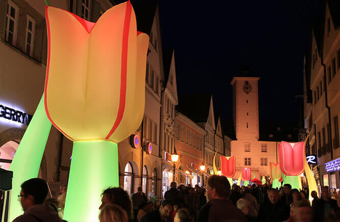 Menschen in der nächtlich illuminierten Burgstraße, der Einkaufsstraße Bad Mergentheims beim Nachtshopping.