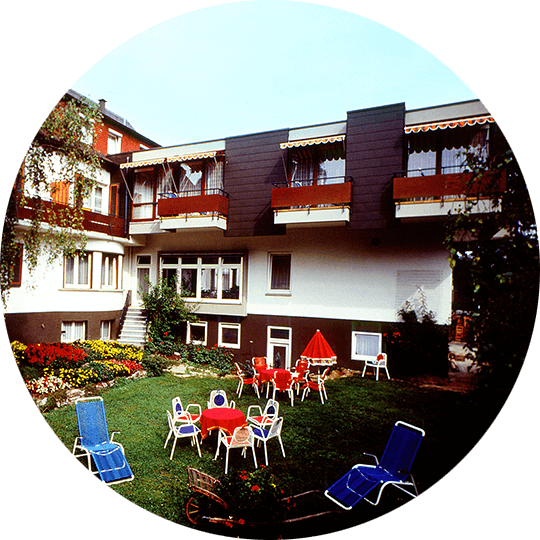 Historisches Bild des Gartens mit Liegestühlen auf der Wiese des Hotel Alexa um 1982